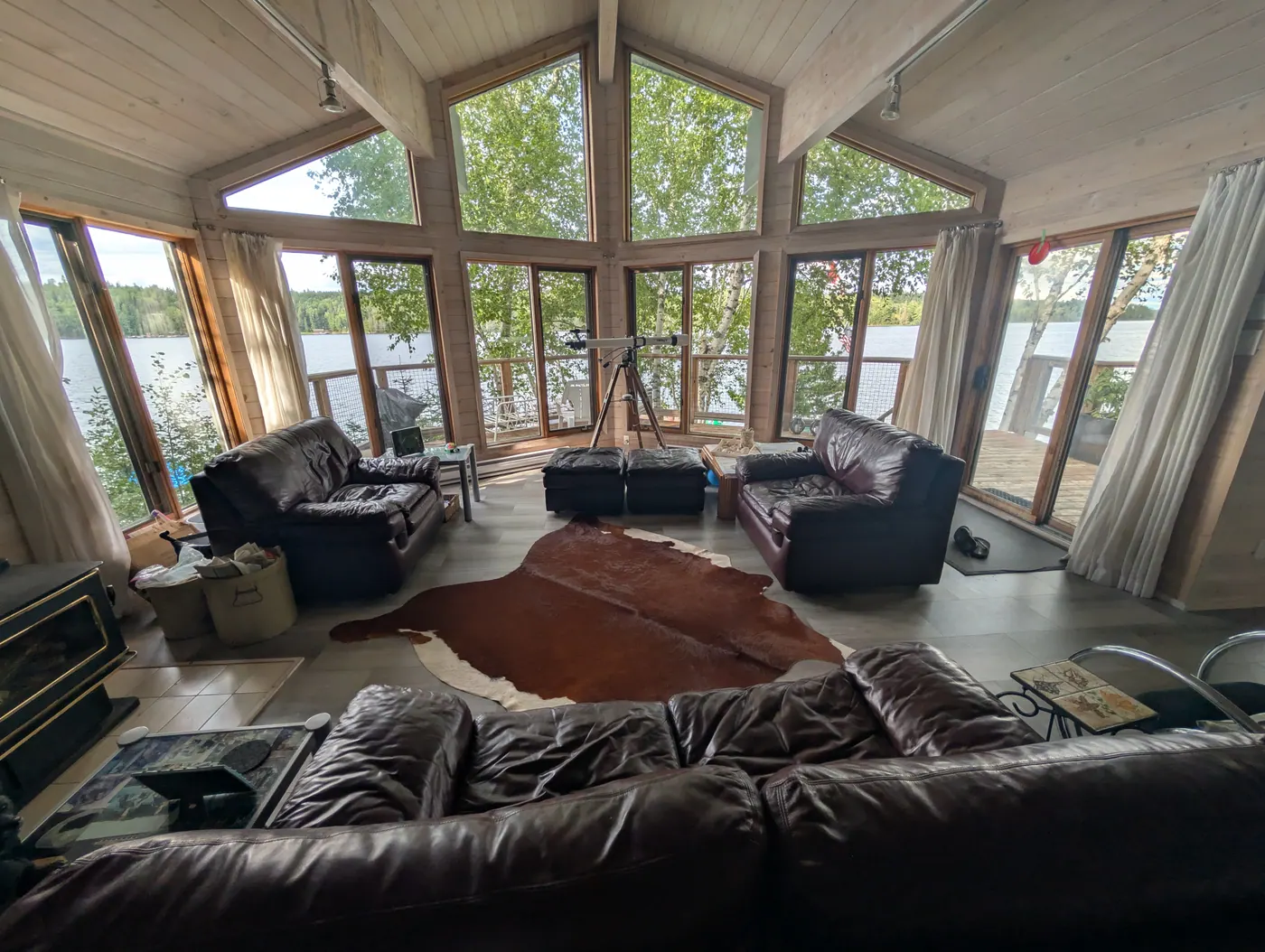 The main living room with leather seating and a wall of windows onto the bay.