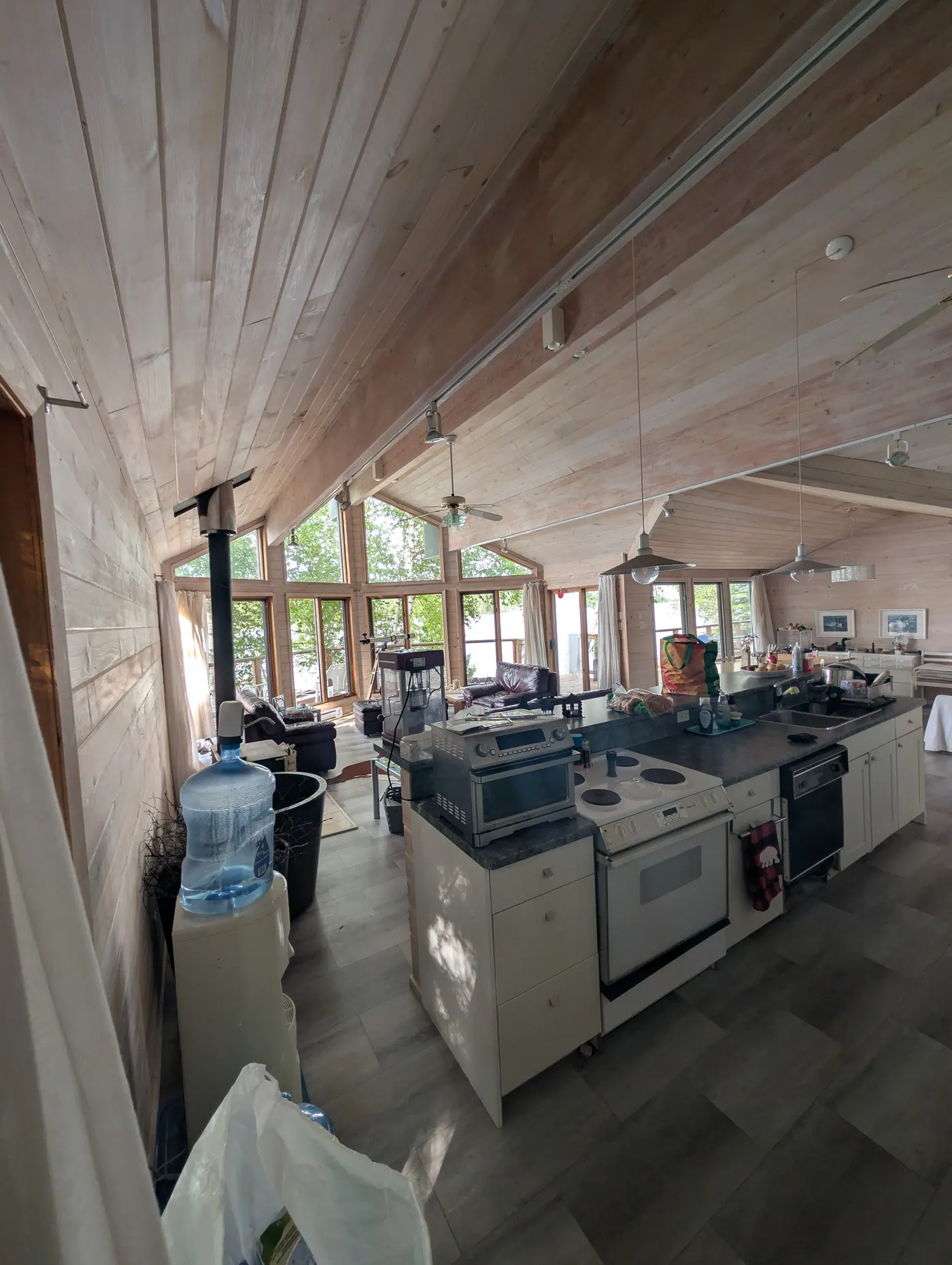 The vaulted main room with kitchen, wood stove and windows to the water.