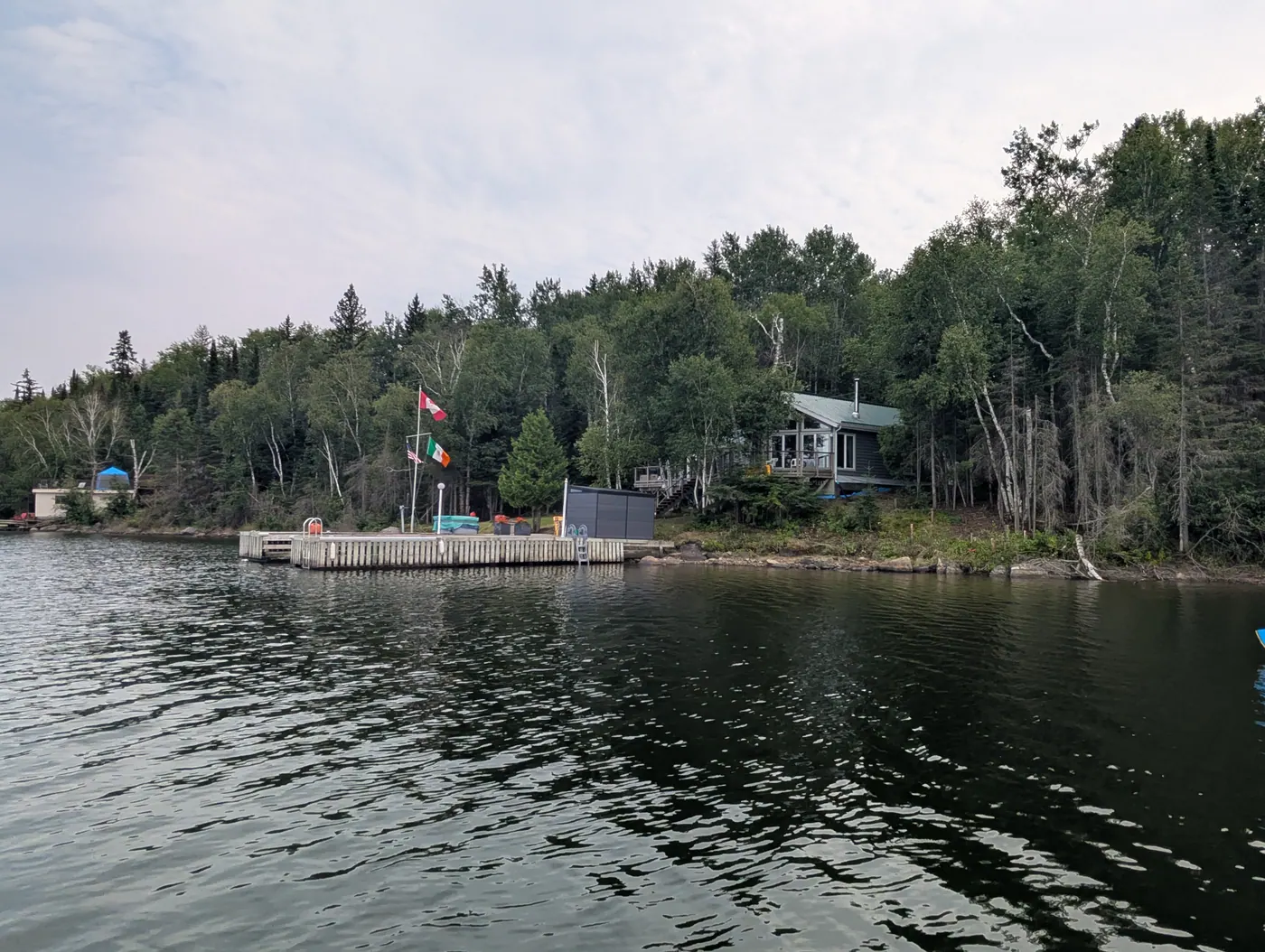 The property and dock seen from the bay under soft cloud.