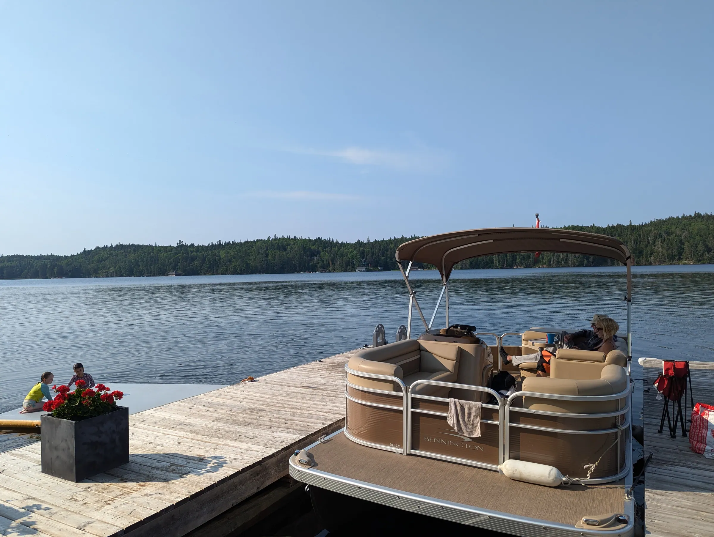 The pontoon boat at the dock with the wide open water of Lake of the Woods beyond.