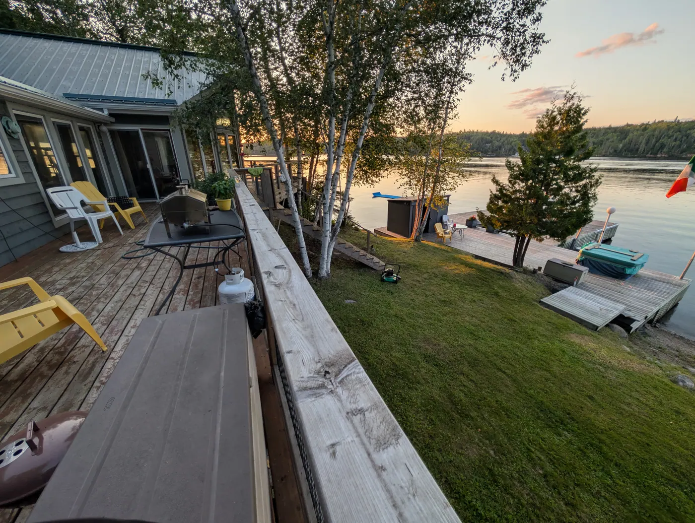 The deck and lawn in low golden light, the dock and boats beyond.