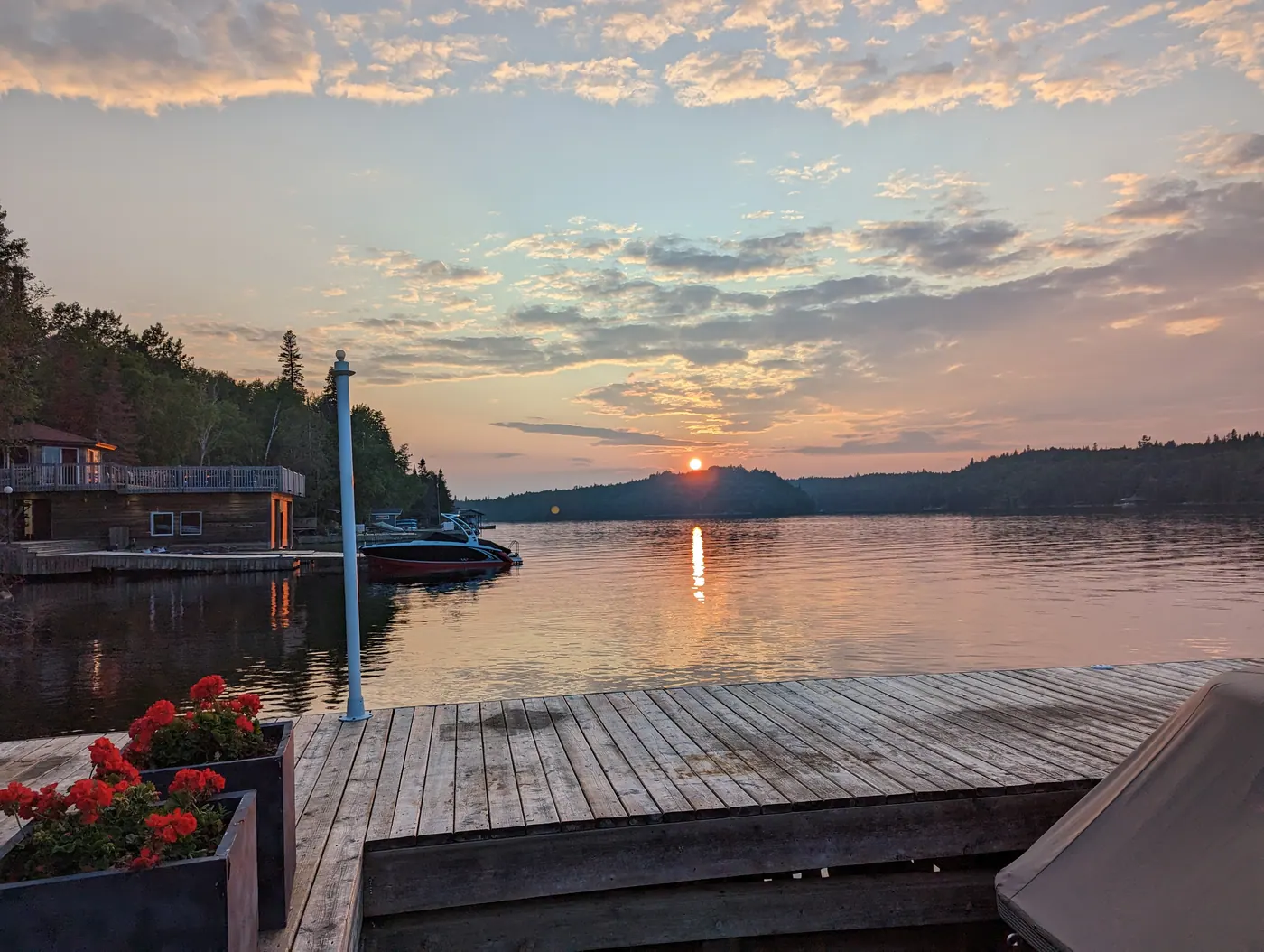 Sunset over the lake from the dock, flowers in planters in the foreground.