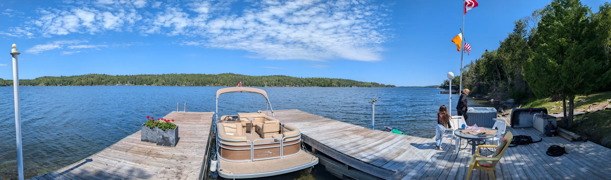Panorama from the dock across Woodchuck Bay, the pontoon boat moored alongside and the far shore in the distance.